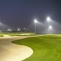 Flere V-TAC LED projektører oplyser en golfbane i tusmørket med palmer i baggrunden.