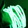 En hånd holder en rulle af LEDlife's grønne, vandtætte neon COB LED-strip, der lyser kraftigt.