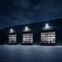 Flere V-TAC LED-projektører lyser lagerbygningens facade op om aftenen.