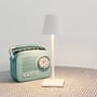 Hvid LED mini bordlampe med tændt lys, placeret ved siden af en retro mintgrøn radio.