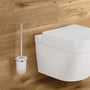 Grohe Essentials toiletbørste med holder i krom og frostet glas, monteret på væg ved siden af et hvidt toilet.