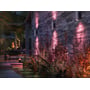 Flere Philips Hue Appear udendørs væglamper i børstet aluminium lyser rosa op og ned på en stenvæg ved terrassen.