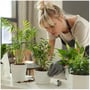 En kvinde passer grønne potteplanter; motivet viser brugen af Kobi VERDI V2 plantelys til planter.
