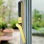 Secuyou Smart Lock Access i messing monteret på en terrassedør med glas og messing greb, omgivet af en have baggrund.