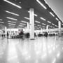 Mange V-TAC LED-armaturer lyser i loftet i en stor terminal med søjler og rejsende.