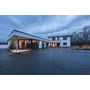 Flere SLV LOGS væglamper i antracit lyser op langs et moderne hus og den brede indkørsel.