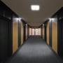 V-TAC LED-sensorlampen er tændt i loftet over en lang gang med mørke vægge.