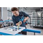 Bosch GCG 18V-310 fugepistol bruges til at fuge en vinduesramme, mens den hviler på et arbejdsbord.