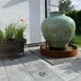 Light By Juul Opal nedgravningsspot ses indbygget i fliser foran et havekar på en solrig terrasse.