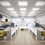 Flere V-TAC LED-paneler i rammer er monteret i loftet over skriveborde på et lyst kontor.