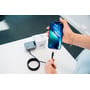 Verbatim Sync & Charge USB-C-kabel med den ene ende holdt ved en smartphone og resten rullet sammen på bordet.