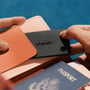 Chipolo CARD trackerkort i charcoal skubbes ned i en pung med orange og lyserøde rum.