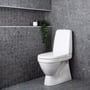Hvidt gulvtoilet fra Gustavsberg Oceanic med skjult S-lås, vist i et badeværelse med mørke fliser.
