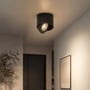 Sort V-TAC 12 W LED-påbygningsspot monteret i loftet og rettet mod væggen i et lyst rum.