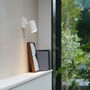Astro Lighting Ascoli Single spotlampe lyser ned over en hylde, monteret på en lys væg ved et vindue.