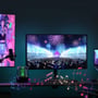 Flere skærme i et gamer-rum oplyst af RGBIC LED strips, der synkroniserer med indholdet, inklusive musiknotationer og lydeffekter.