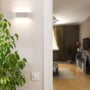 Grå V-TAC LED udendørs væglampe monteret på en lys væg, hvor den spreder lys opad og nedad.