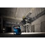 Bosch GLI 18V-3000 arbejdslampe lyser et byggeareal op, mens en håndværker arbejder på et stillads.
