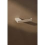 Enkel Metallbude Tuali toiletrulleholder i hvid metal vist med en skyggeeffekt på en mørkere væg.