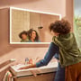 Hansgrohe Xarita E spejl, 1200x700mm, med integreret LED-lys og IR-sensor, vist med en mor og barn ved vasken.
