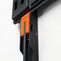 Nærbillede af Vogel's Click & Lock-system på vægbeslaget, der viser den orange låsemekanisme og detaljer i sort plast.