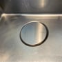 Lavabo Design Cover, rund afløbsskjuler i rustfrit stål på Ø115 mm, ligger monteret over afløbet i en stålvask.