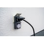 Brennenstuhl udendørs timer monteret på en hvid væg, med et sort kabel tilsluttet og beskyttelsesklappen åben.