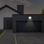 V-TAC LED projektør med PIR sensor oplyser en garageindkørsel om natten, med varmt hvidt lys.