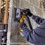 DeWalt Flexvolt rillefræser DCG200NT-XJ i brug til at skære en kanal i en betonvæg, med støvudsugning tilkoblet.