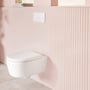 Villeroy & Boch ViConnect E200-vægtryk monteret over et hvidt toilet mod en lyserød, rillet væg.