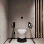 Nichba toiletstøtter ses på begge sider af et toilet; den sorte støtte til højre har en toiletrulle.