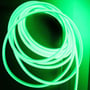 LEDlife grøn neon COB strip viklet i en cirkulær form, der viser dens lysende egenskaber på en mørk, tekstureret overflade.
