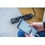 Brennenstuhl Ecolor forlængerledning med tænd/sluk-knap og to USB-opladere, mens en person holder en smartphone.