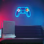 Stemningsfuldt gaming-rum med et blåt neon gamepad skilt monteret på væggen over en sofa og et skrivebord.