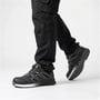 Activewear Knox 5101 sikkerhedssandal i sort ses fra siden på fødder, mens den ene sko løftes og viser sålen.