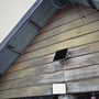 V-TAC LED projektør med monteret solpanel fastgjort til en træbeklædt væg ved et hus.