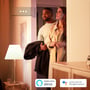 Philips Hue E14 LED-kertepære illustreres i en varmt oplyst entré med personer og logoer for stemmestyring.