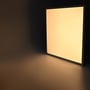 Neutral LED-panel lyser stående mod en mørk væg, hvor den jævne flade kaster lys ned på gulvet.