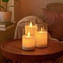 LEDlife LED bloklys i glas med vippende flamme, sæt af 3 stk på et rundt bord med hyggelig baggrundsbelysning.