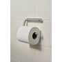 Knud Holscher toiletrulleholder fra d line set tæt på med rulleholderens tap og toiletrulle på flisevæg.