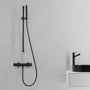 Stilfuldt Scandtap Steel Pleasure 1 Shadow termostatarmatur i matsort med brusehoved, monteret på marmoreret væg ved siden af sort håndvask.