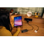 En person oplader en tablet og en smartphone med Verbatim 65W GaN opladeren i et køkkenmiljø.