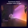 Philips Hue Lightstrip Gradient monteret bag et TV, skaber en stemningsfuld lysoplevelse med flydende farveovergange i et moderne rum.