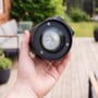 LEDlife Avero GU10-væglampe holdt i hånden med fronten og lyskilden synlig foran en terrasse.