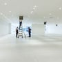 To håndværkere installerer loftslamper i et stort, lyst kontorlokale med mange spots og ventilationsanlæg.