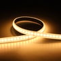 Ansell Lighting U-Cell LED strip med varmt hvidt lys, 9,6W/m, 48V og IP65-klassificering, vist i en buet form på en mørk baggrund.