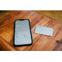 Verbatim My Finder Card ligger ved siden af en iPhone, der viser 'Find My'-appen på et bord.