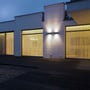 To V-TAC LED-væglamper i grå lyser opad og nedad på husets facade med varmt lys om aftenen.