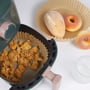Nordic Quality rundt bagepapir brugt i en airfryer med sprøde nuggets, og to kager på et stykke bagepapir ved siden af.