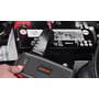 OSRAM BATTERYstart 200 med powerbank holdes ved et bilbatteri, mens en hånd betjener tændknappen.